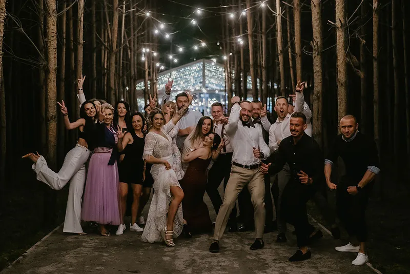 Goście weselni pozują do wspólnego zdjęcia podczas wieczornej zabawy