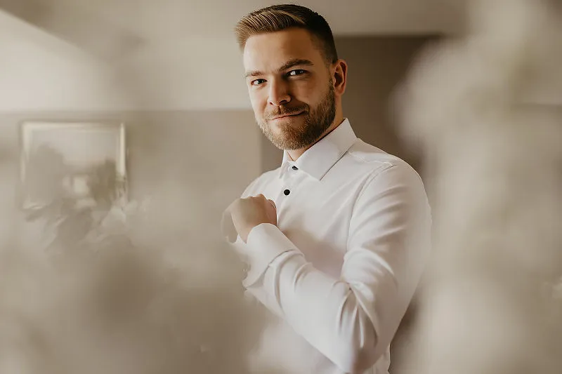 Pan Młody poprawia mankiet koszuli podczas przygotowań do ślubu