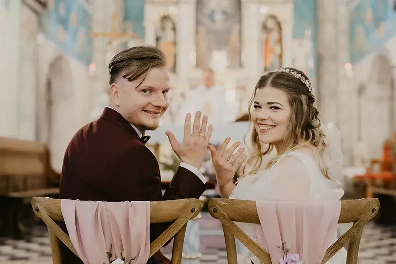 Para młoda odwracająca się do obiektywu podczas ceremonii w kościele