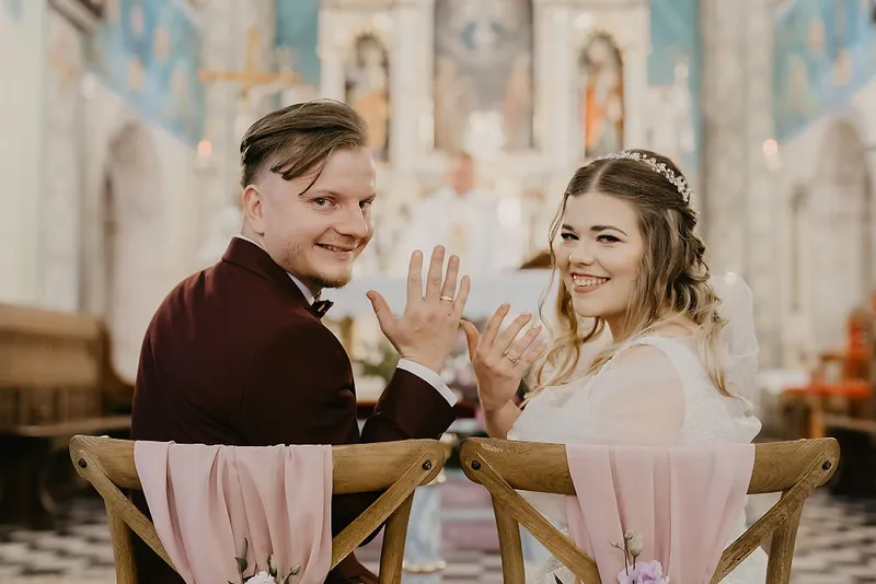Para młoda odwracająca się do obiektywu podczas ceremonii w kościele