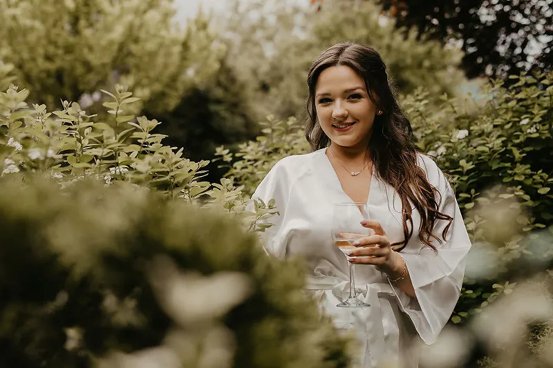 Panna młoda z kieliszkiem podczas przygotowań ślubnych w ogrodzie
