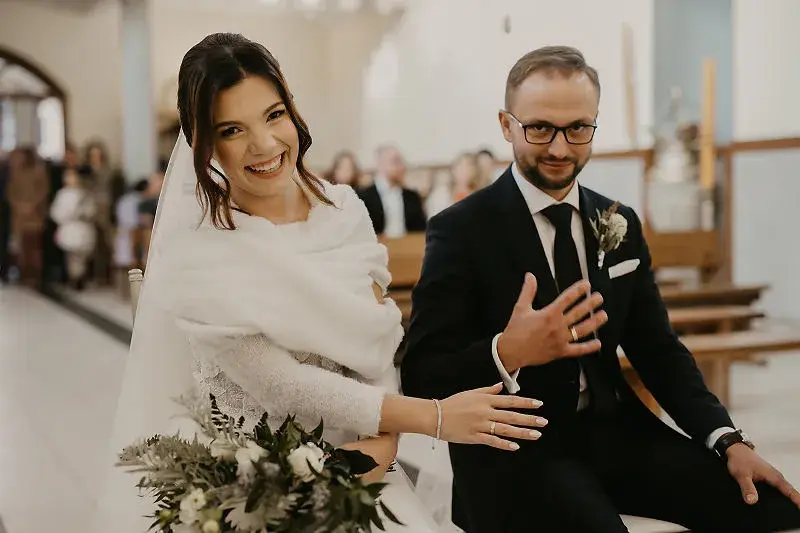 Para młoda podczas ceremonii ślubnej pokazuje obrączki po zarezerwowaniu terminu i usługodawców