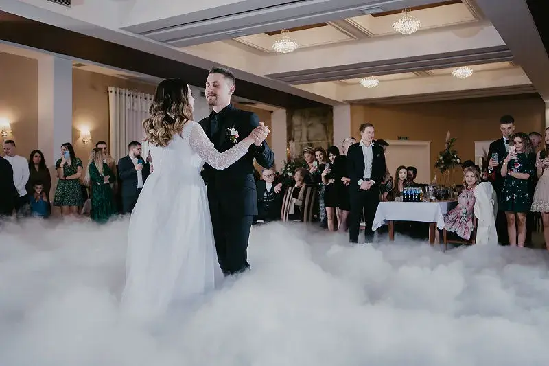 Para Młoda tańcząca pierwszy taniec w sali weselnej otoczonej gośćmi