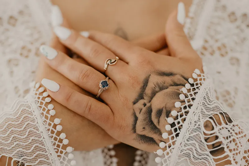 Dłoń panny młodej z pierścionkiem na tle koronkowej sukni ślubnej Dłoń panny młodej z pierścionkiem na tle koronkowej sukni ślubnej