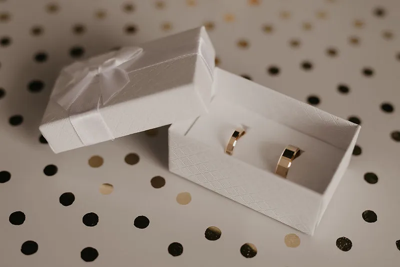 Obrączki w białym pudełku na tle dekoracyjnego stołu Obrączki w białym pudełku na tle dekoracyjnego stołu