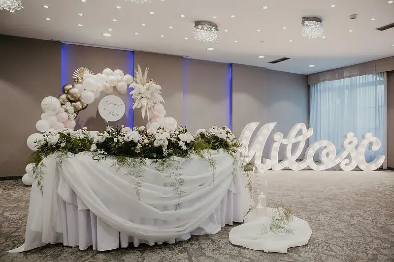 Jasna sala weselna z udekorowanym stołem pary młodej